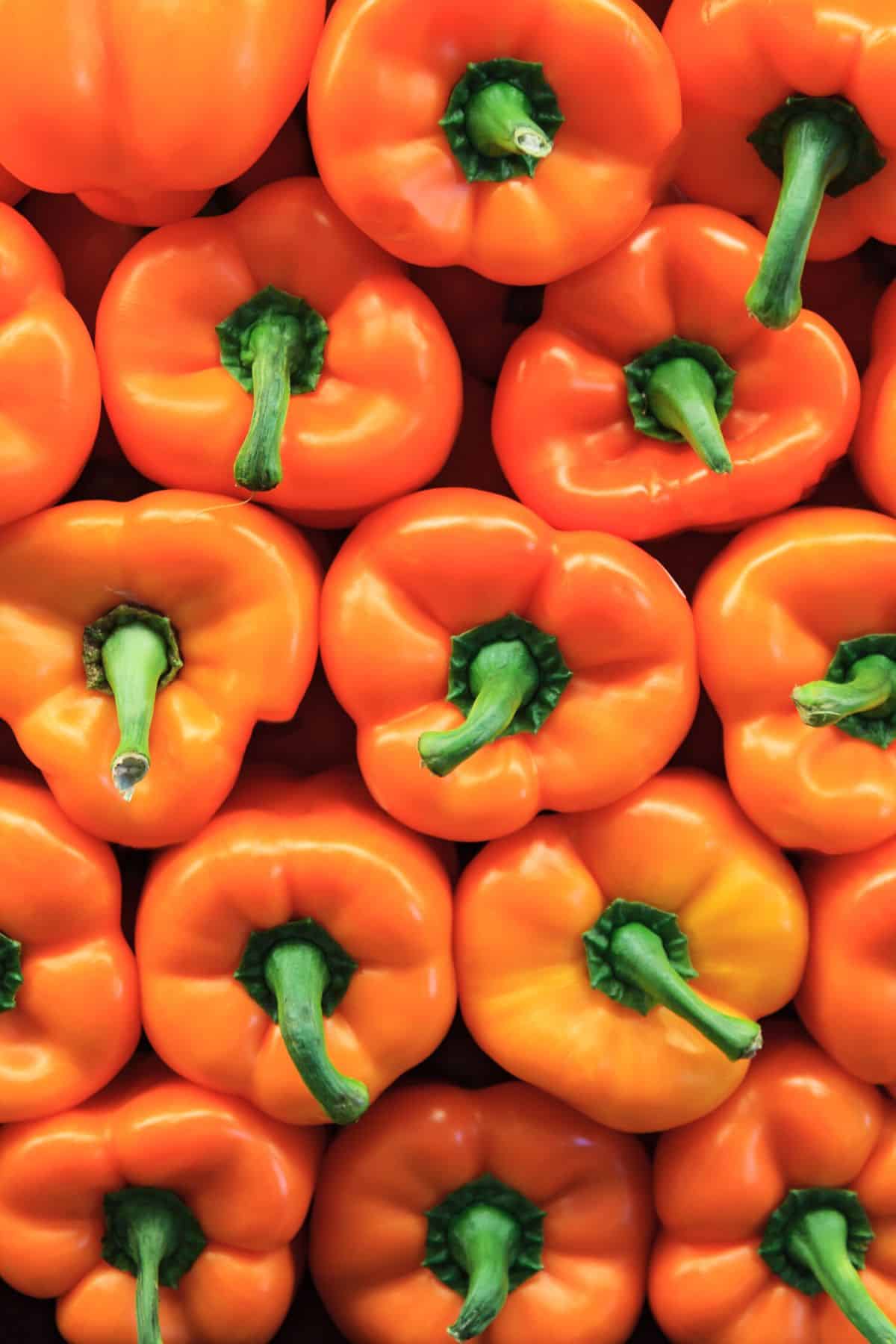 a stack of orange bell peppers.