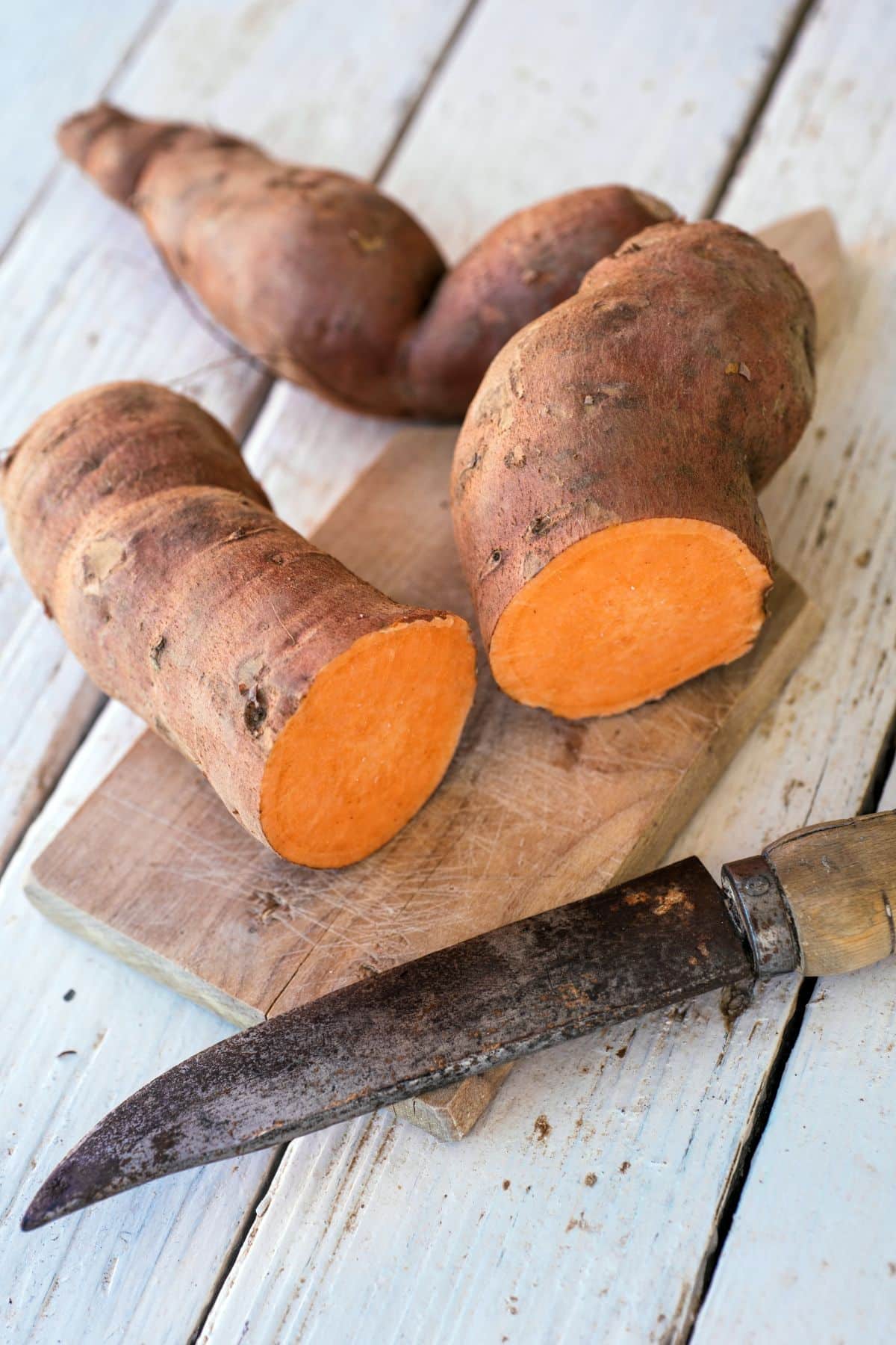 a sweet potato sliced open on a cutting board.