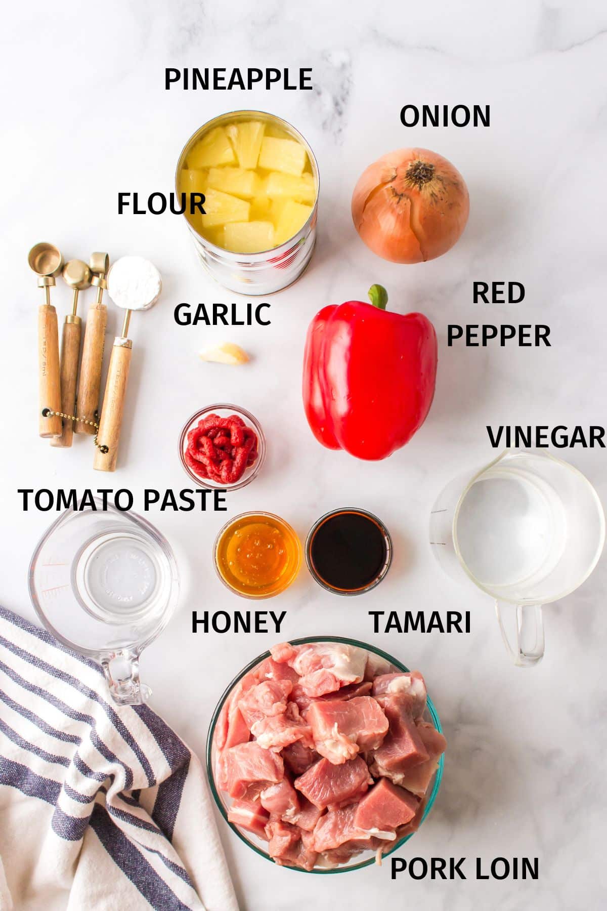 Ingredients to make sweet and sour pork on a white surface.