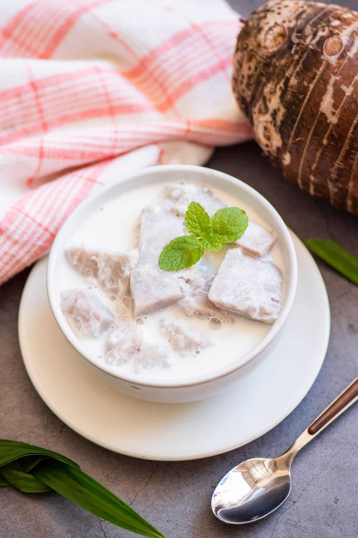 A small white bowl of taro milk topped with mint.