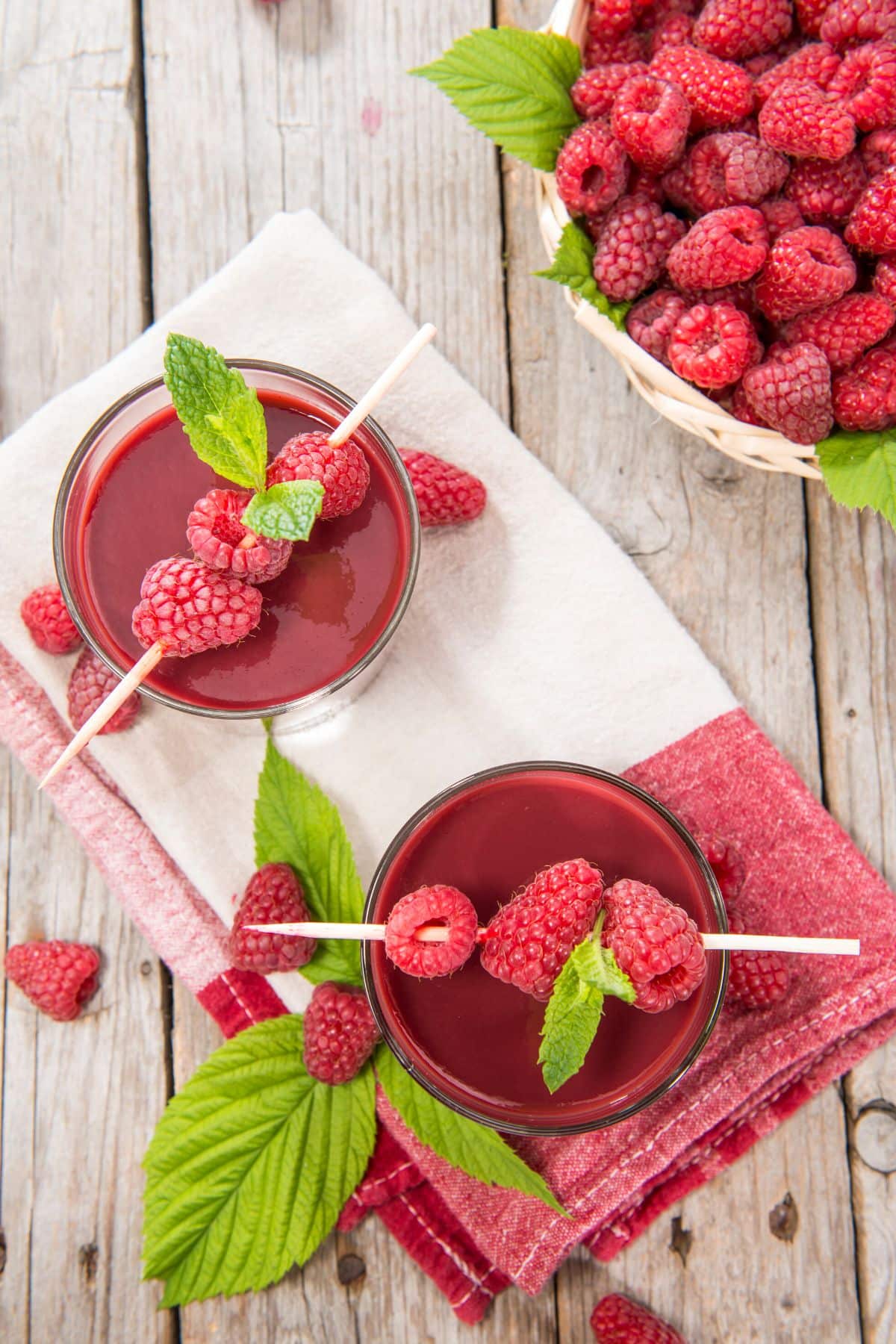 Top view of two glasses of raspberry juice on a towel.