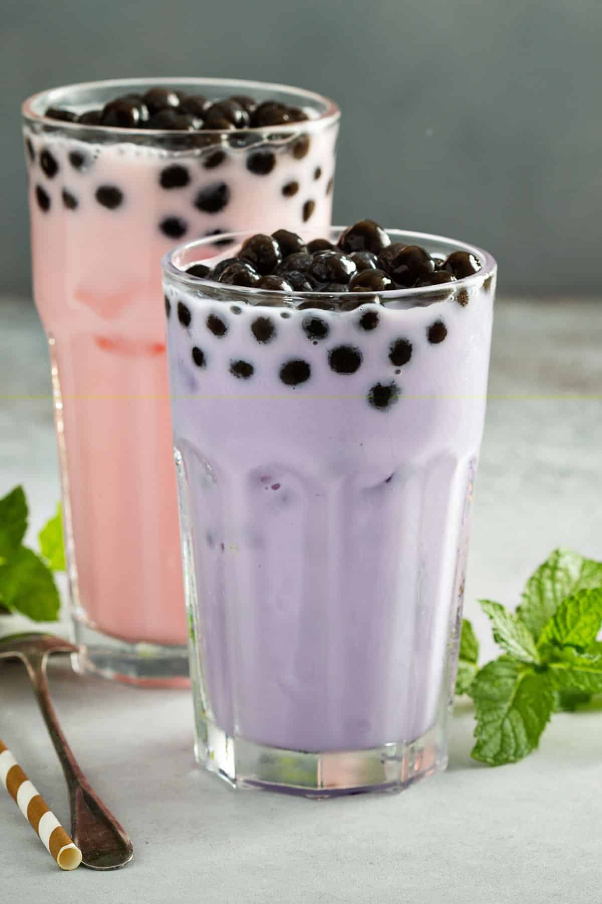 Two glasses of taro milk with boba pearls.