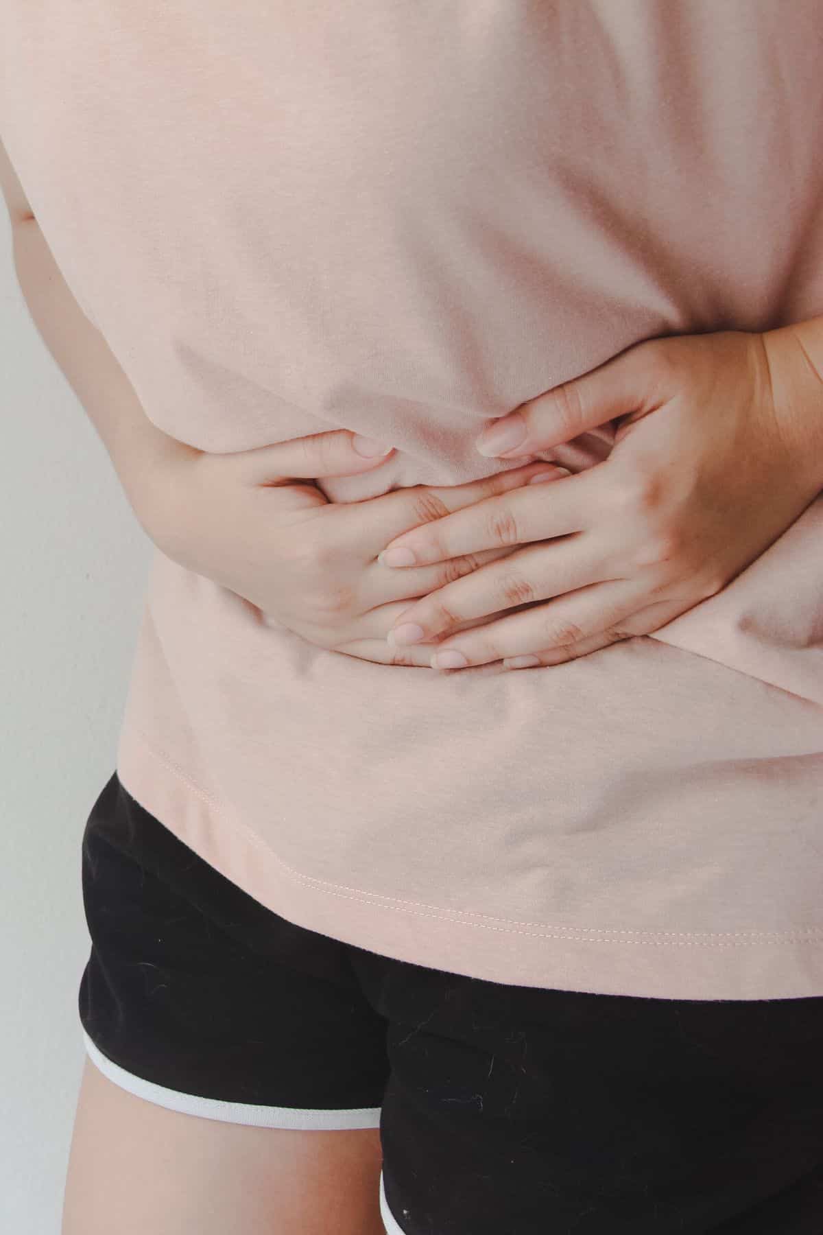 young woman holding her stomach as if she is in pain.