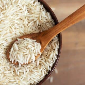 a wooden bowl of basmati rice with a wooden spoon.