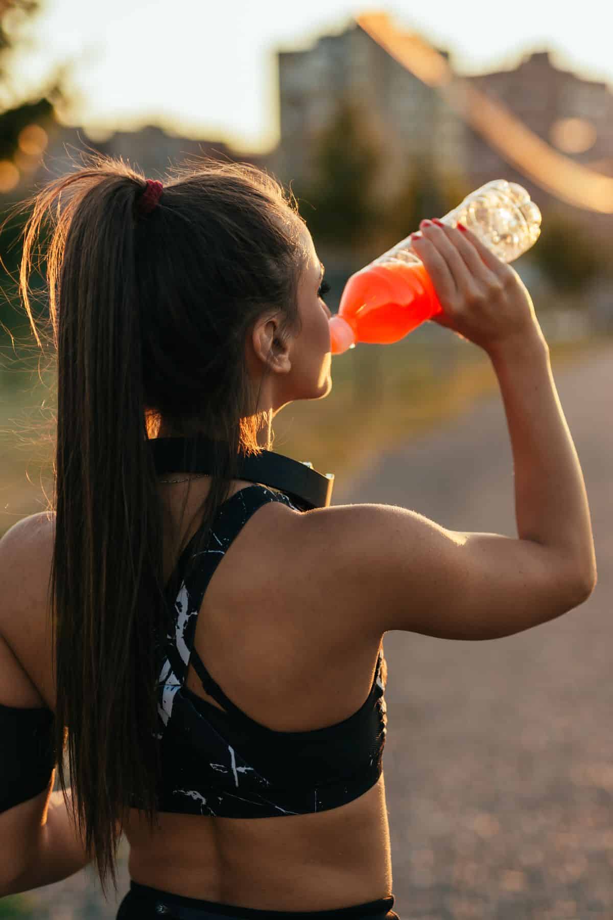 a woman drinking a sports drink.