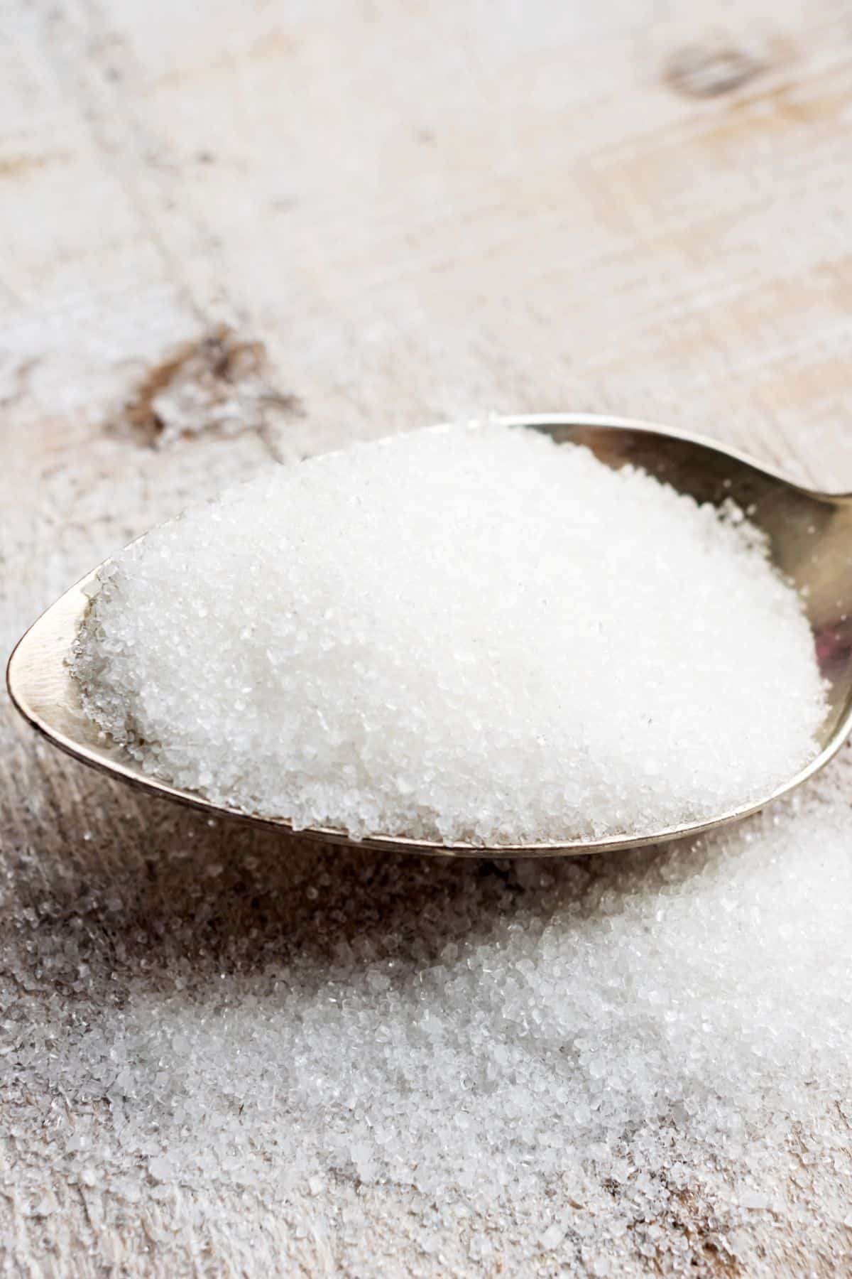 a spoon full of sucralose spilling onto a wooden table.