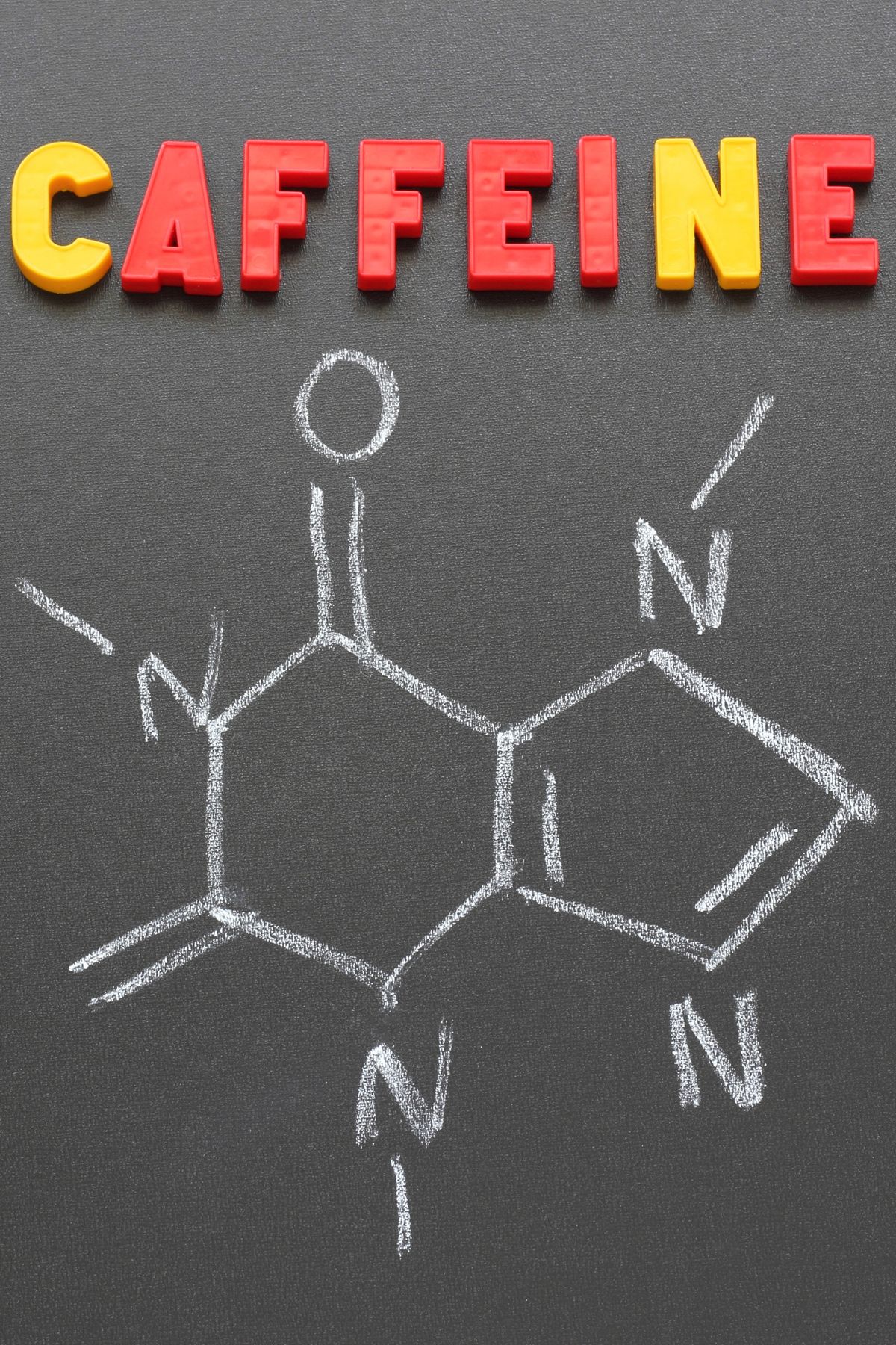the word caffeine on a blackboard over a chalk drawing of the compound.