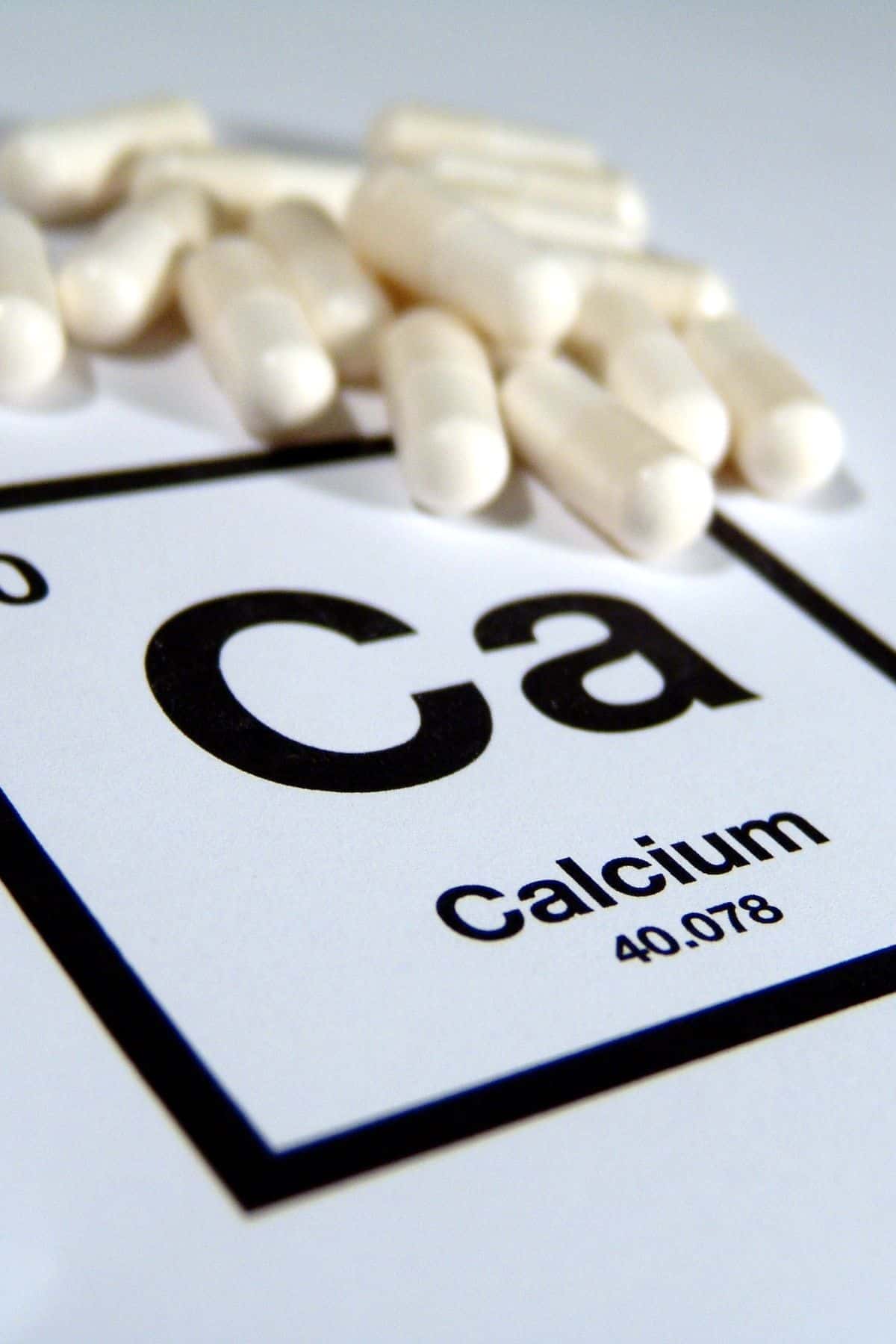 calcium supplements on top of a piece of the periodic table.