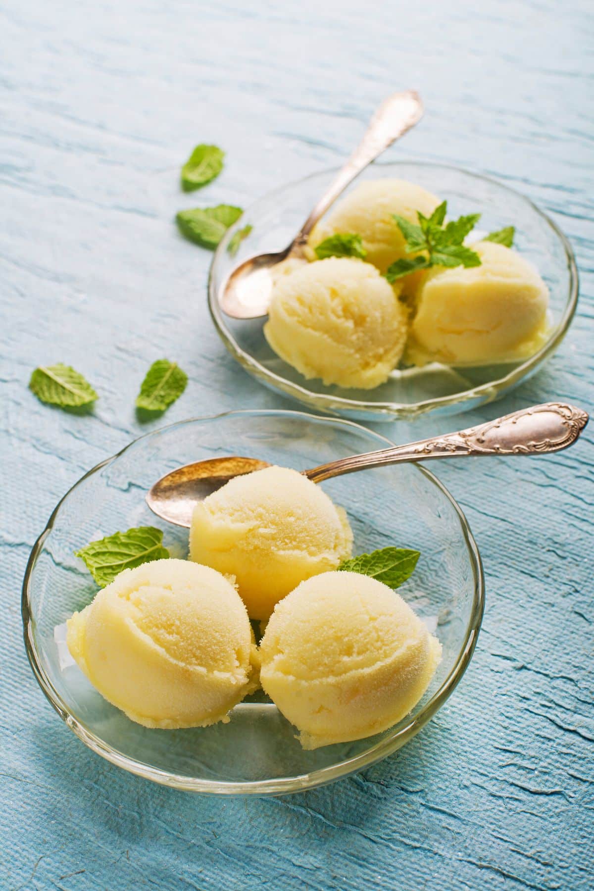 mango sorbet with mint served in two bowls with spoons.