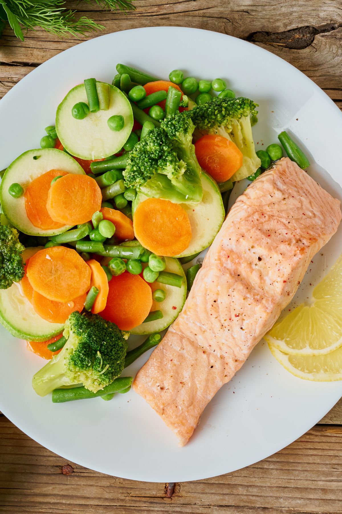 steamed vegetables with salmon served on white plate.