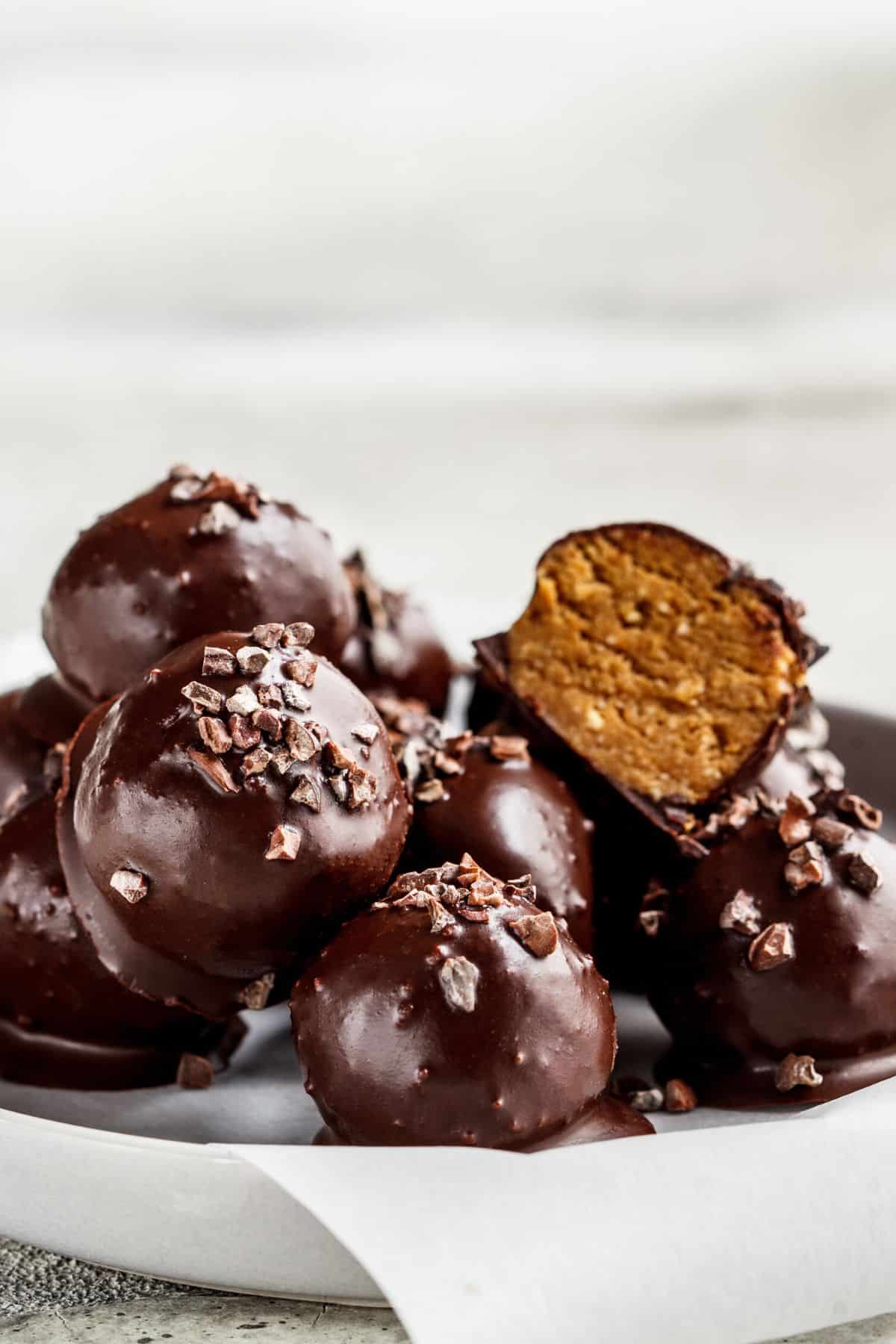 tahini truffles in a bowl with cocoa nibs on top.