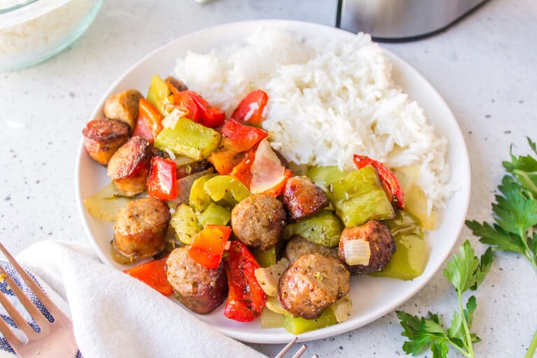 air fryer sausage and peppers on a white plate with rice.