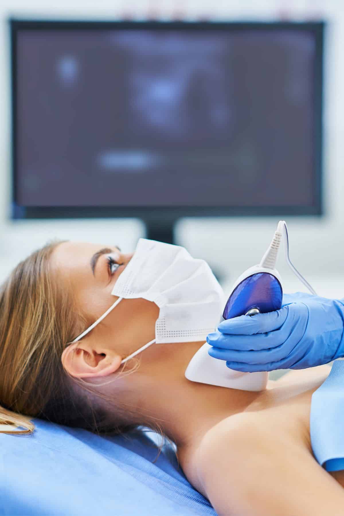 a woman having her thyroid examined.