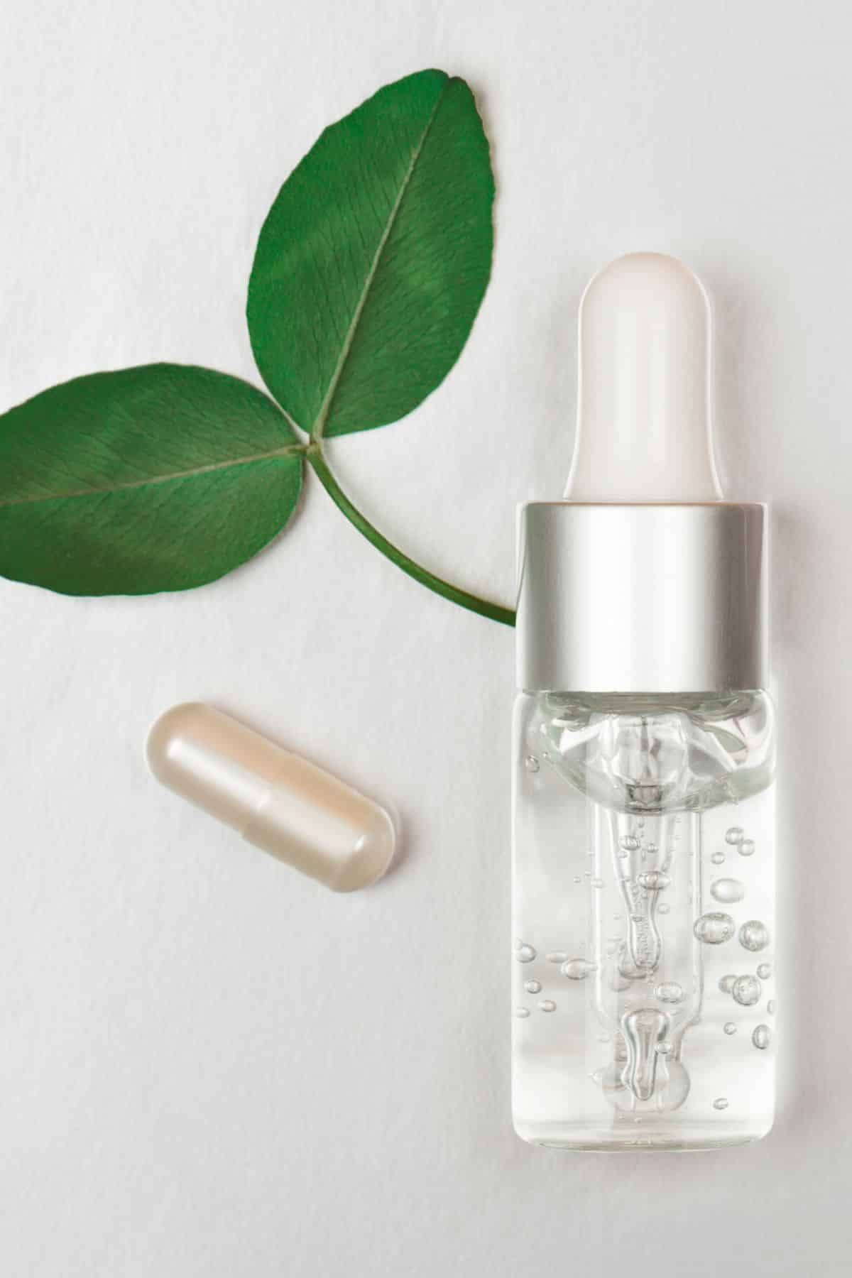a bottle of hyaluronic acid next to a supplement and a green leaf.