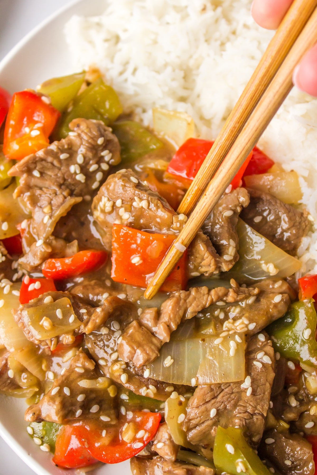 chopsticks holding a piece of bell pepper and steak.