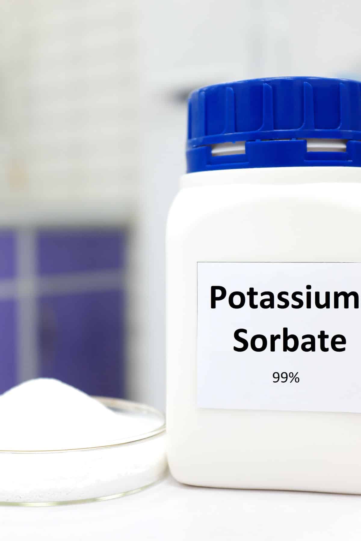 a bottle of potassium sorbate next to a beaker full of potassium sorbate.