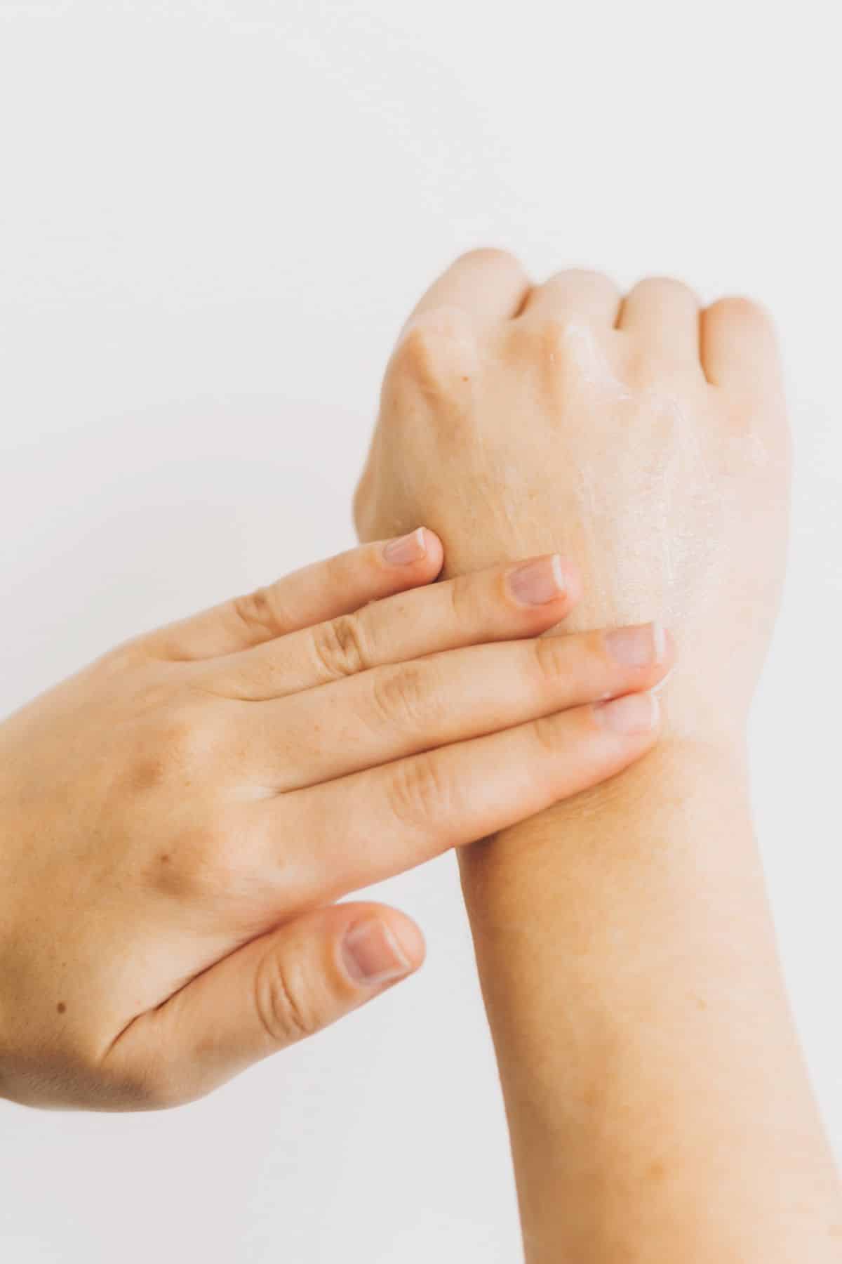 a woman rubbing a patch of dry skin on her hand.