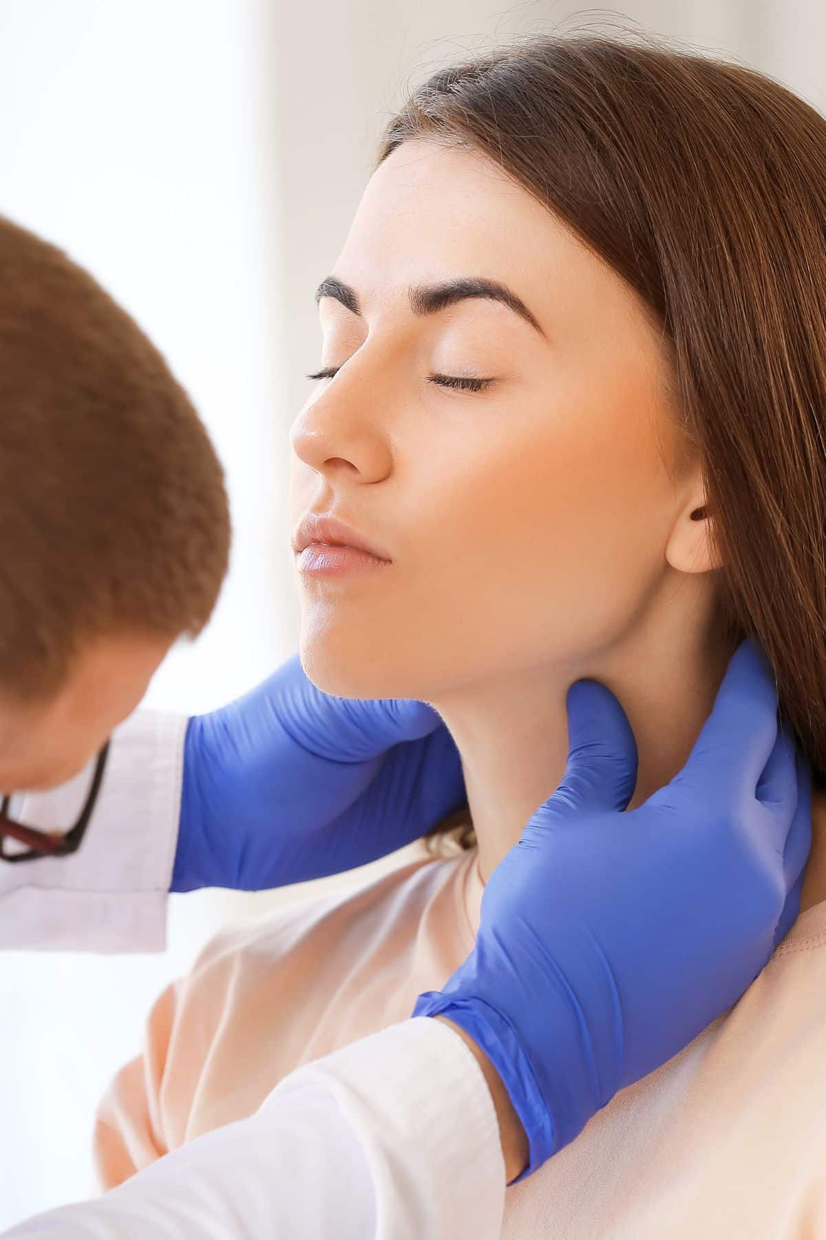 a woman having her neck examined by a doctor.