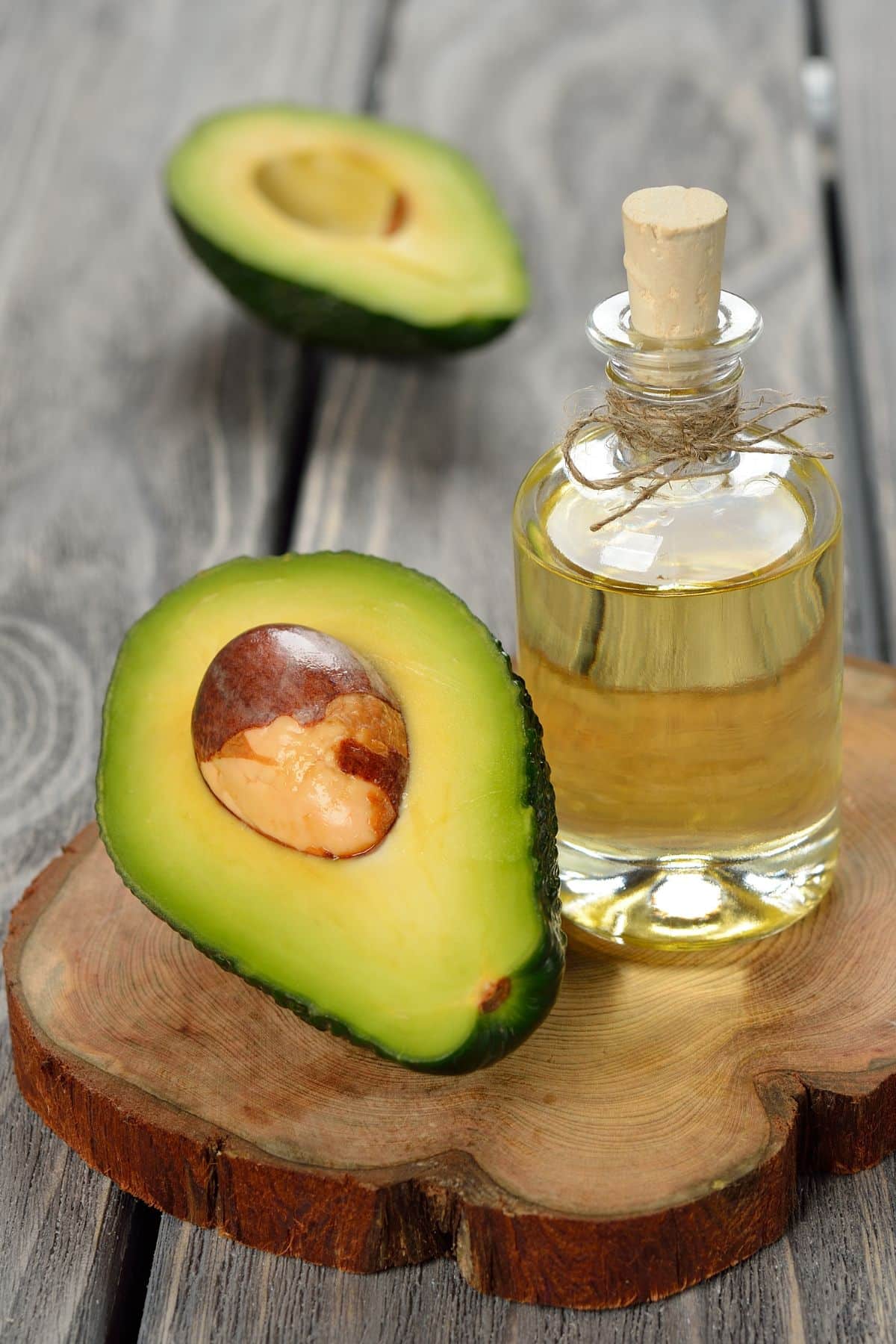 a jar of avocado oil next to a sliced avocado.