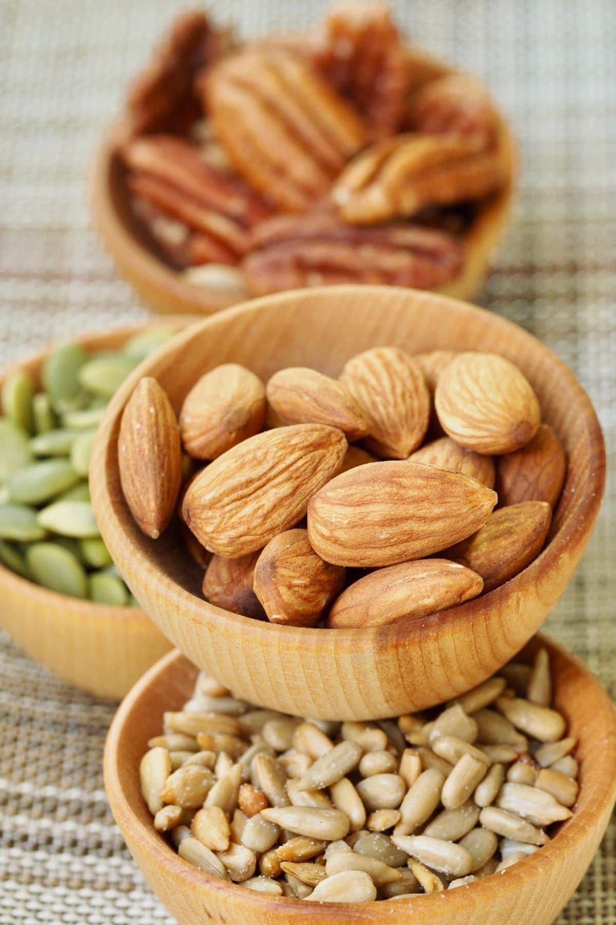 a variety of nuts and seeds in individual bowls.