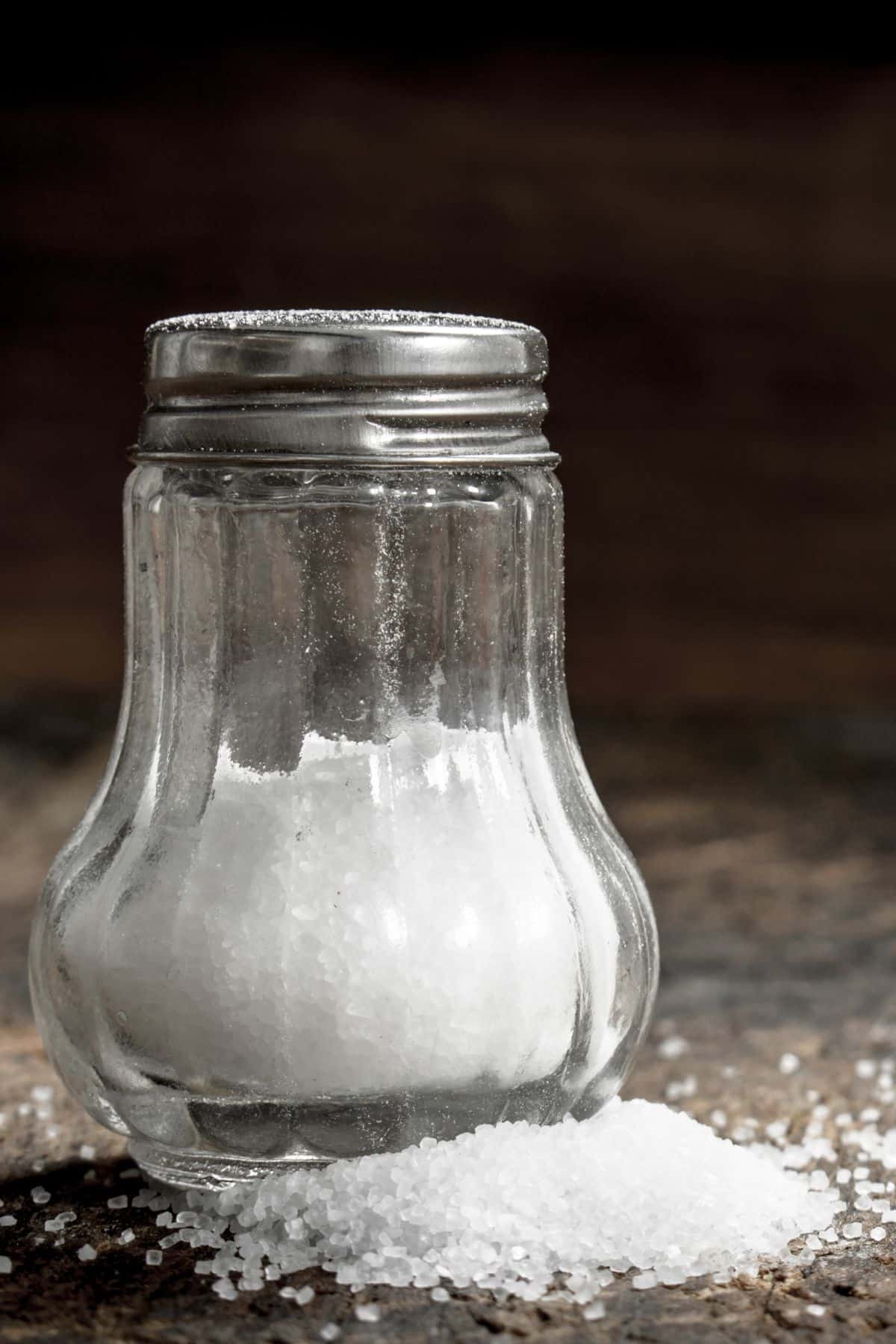 a half full salt shaker with salt around the base.
