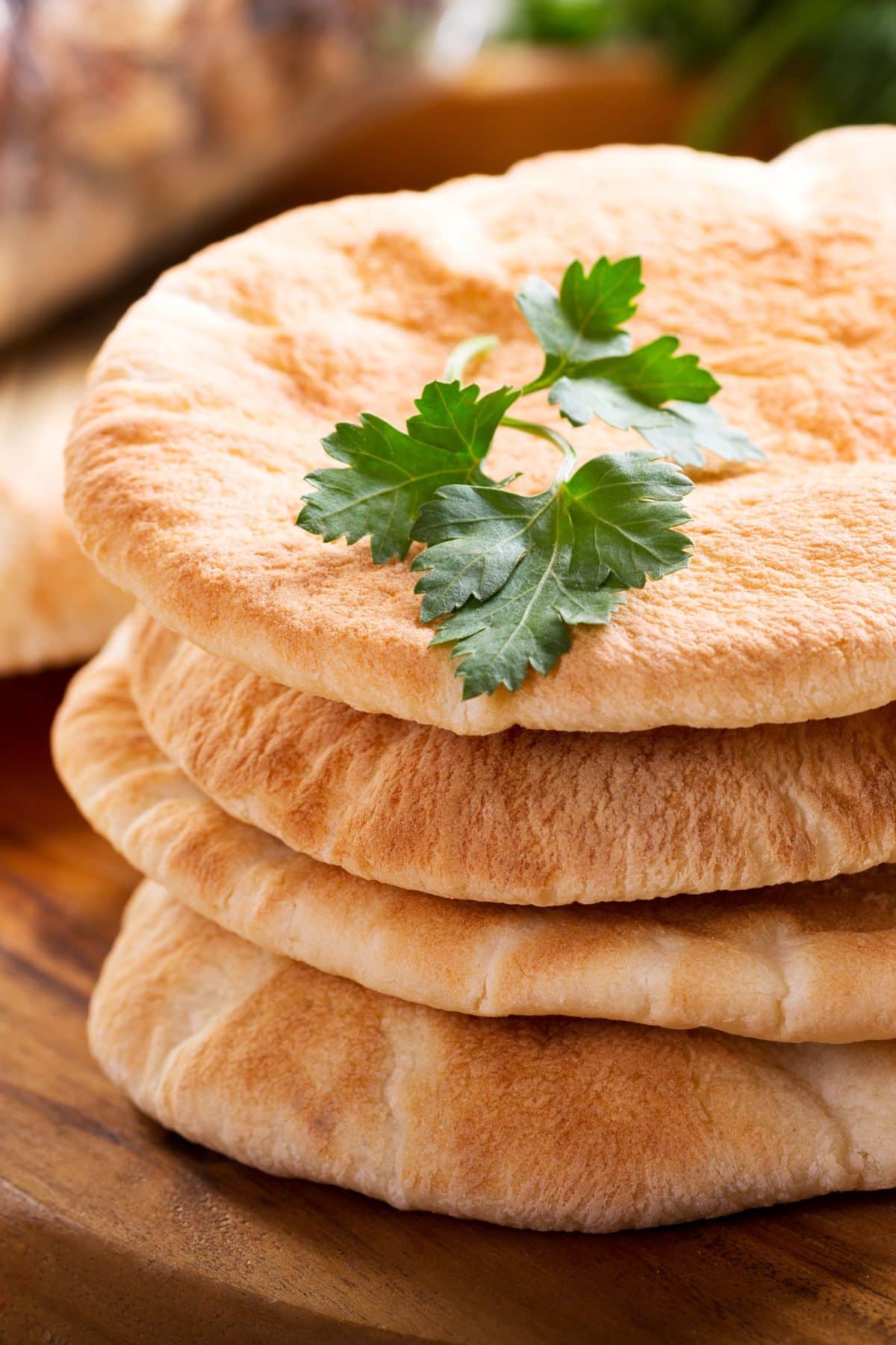a stack of four pieces of pita bread on a wooden surface.