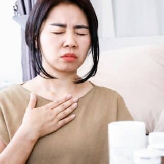 a woman touching her neck with her eyes closed.