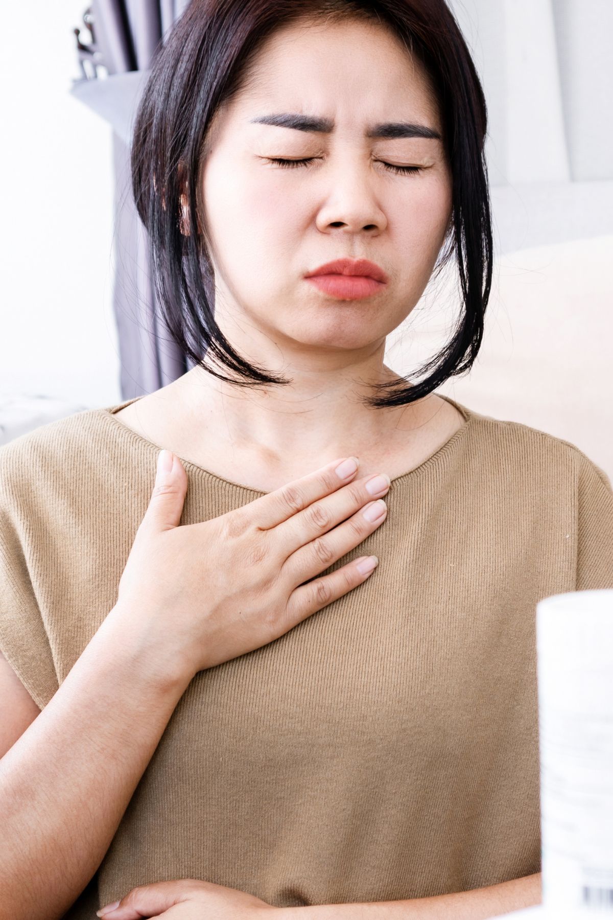 a woman touching her neck with her eyes closed.