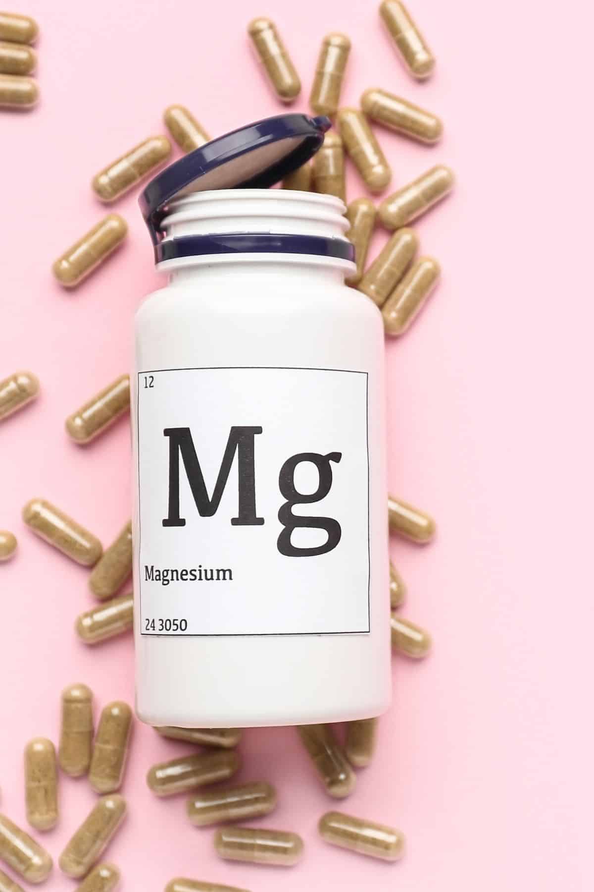 a bottle labled "Mg" surrounded by tablets of magnesium.