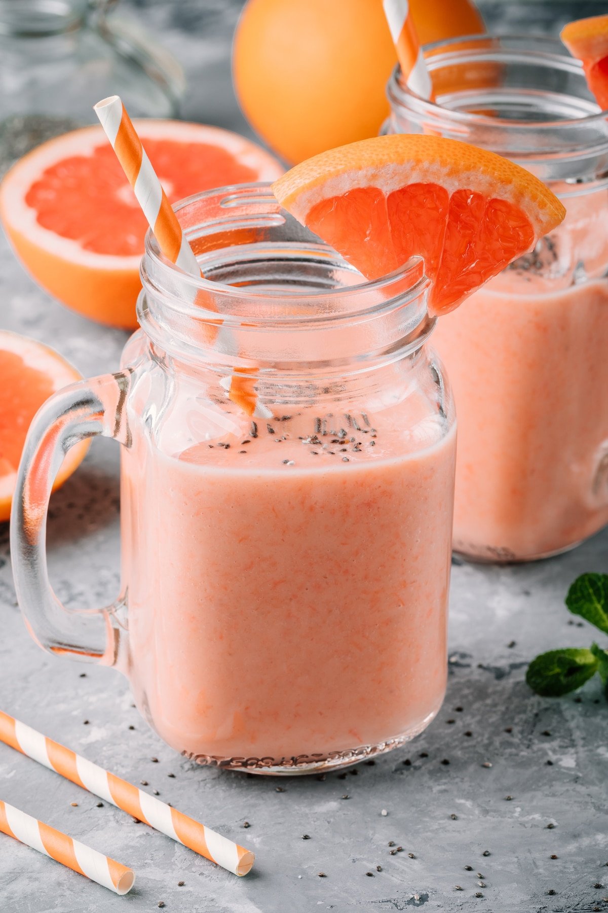 two glasses of pretty pink grapefruit smoothie on table.