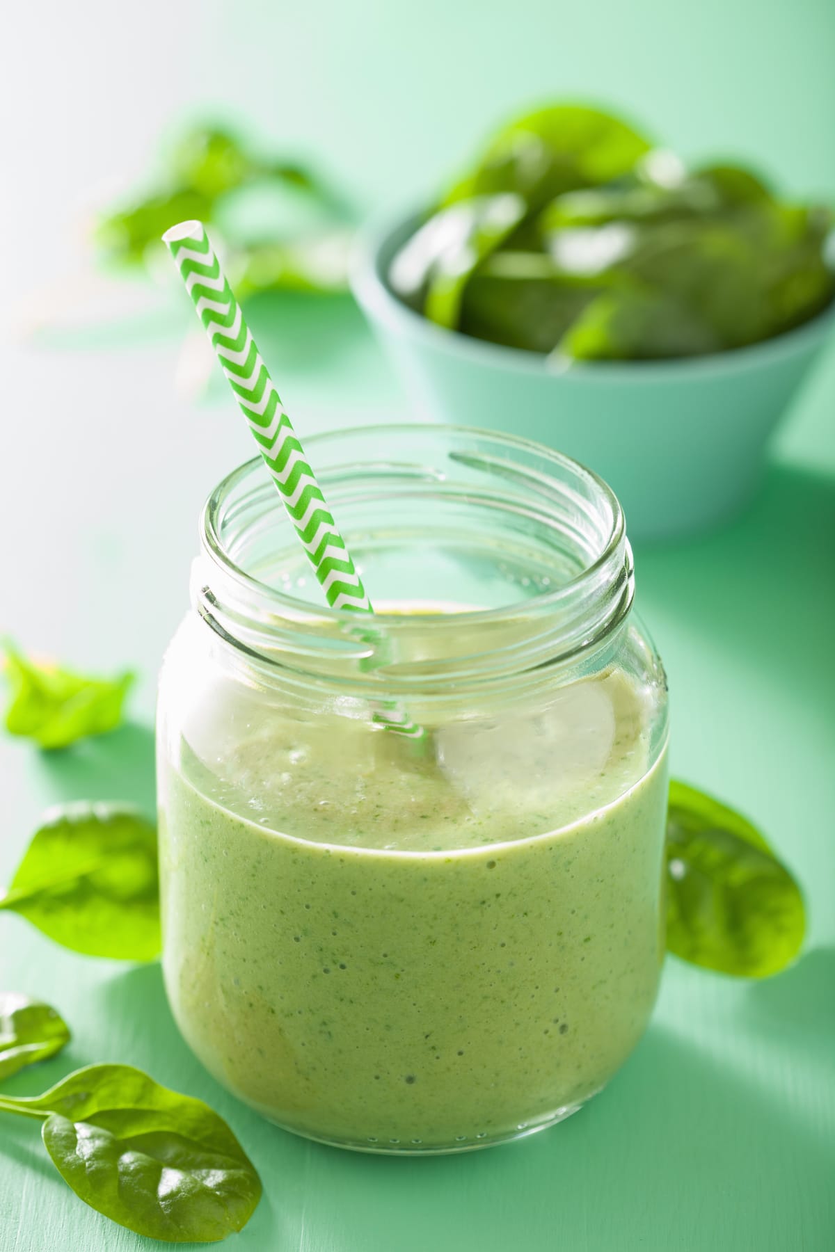 healthy green smoothie with spinach, mango, and banana in a glass jar.