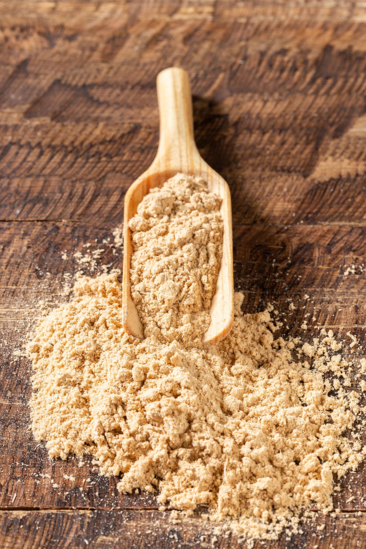 maca powder pouring out of a scoop onto a table.