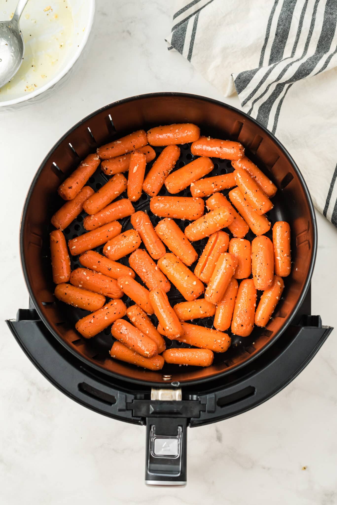 baby carrots in air fryer basket ready to be cooked.