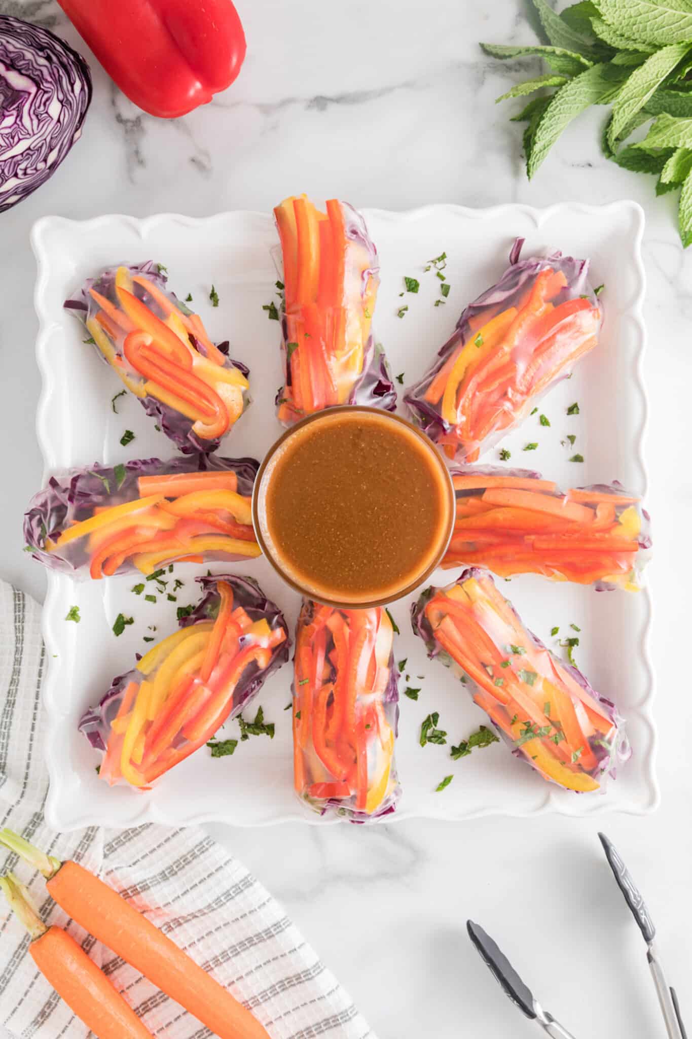 vegan summer rolls on plate with peanut dipping sauce in bowl. 