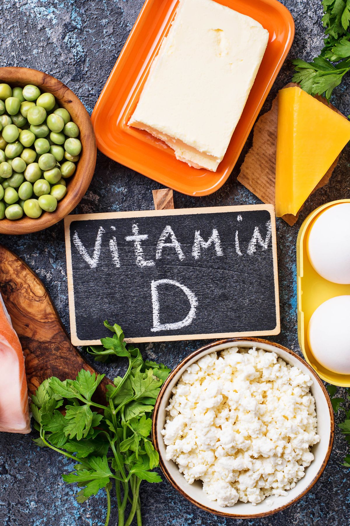 a variety of foods high in vitamin d surrounding a chalkboard sign of "vitamin d".