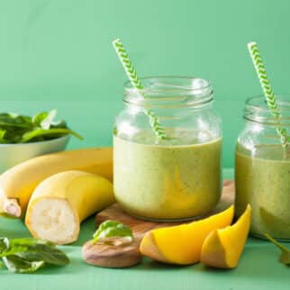 two weight loss green smoothies next to bananas and mango.