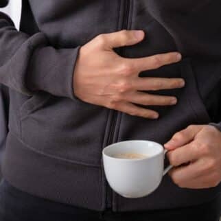 a man holding a cup of coffee with the other hand on his stomach.