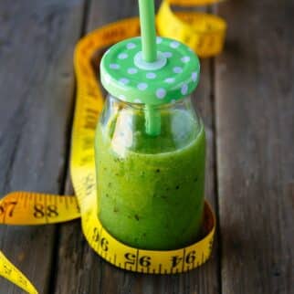a green smoothie in a jar, surrounded by a measuring tape.