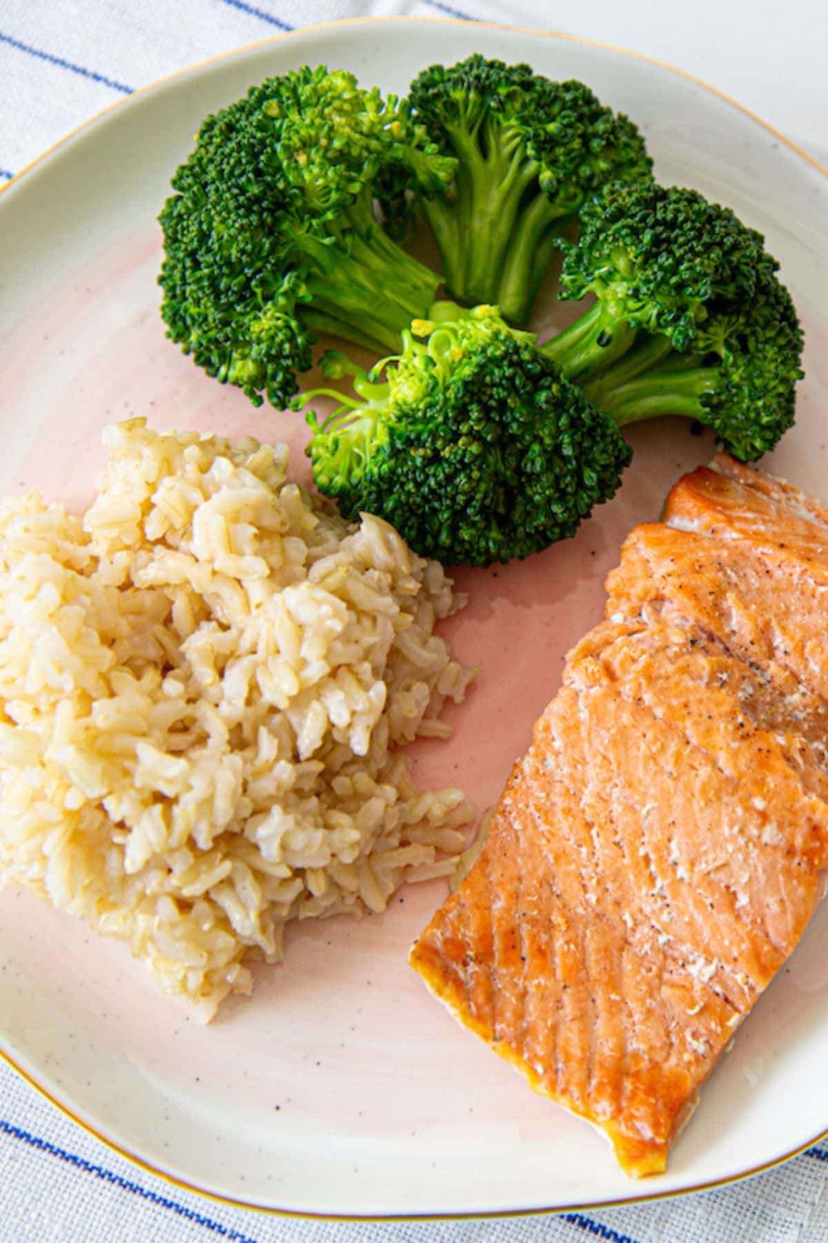 bone broth rice on a plate with broccoli and salmon.