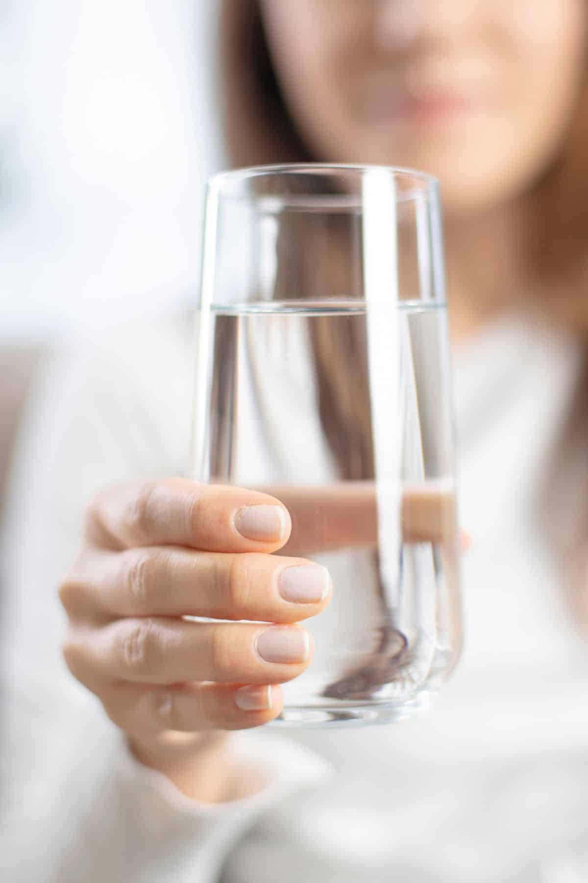 a woman holding a glass of water.