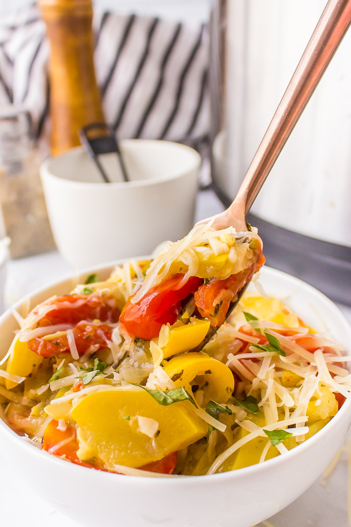 a fork full of yellow squash and tomatoes.
