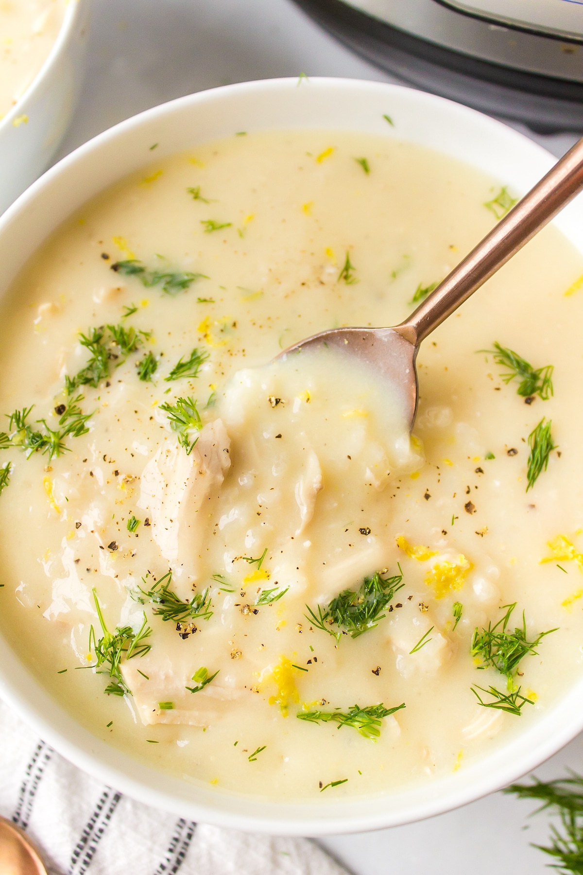 a spoon taking out a scoop of avgolemono soup.