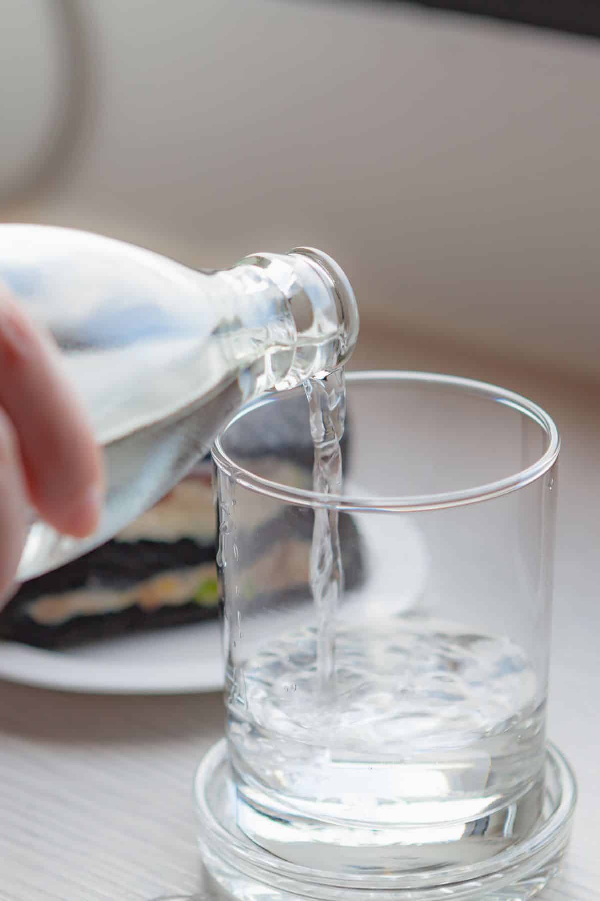 a person pouring water into a glass.
