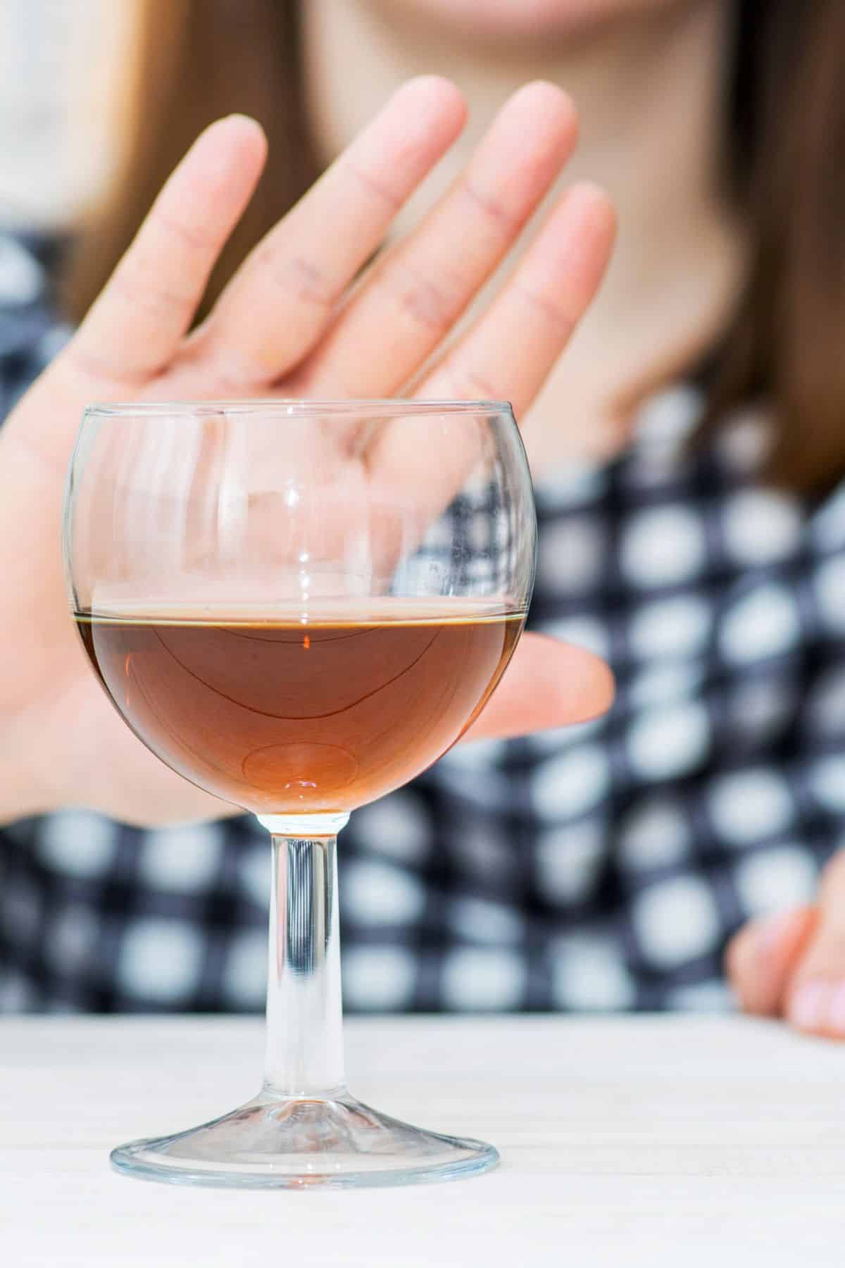 a woman holding her hand out in front of an alcoholic beverage.
