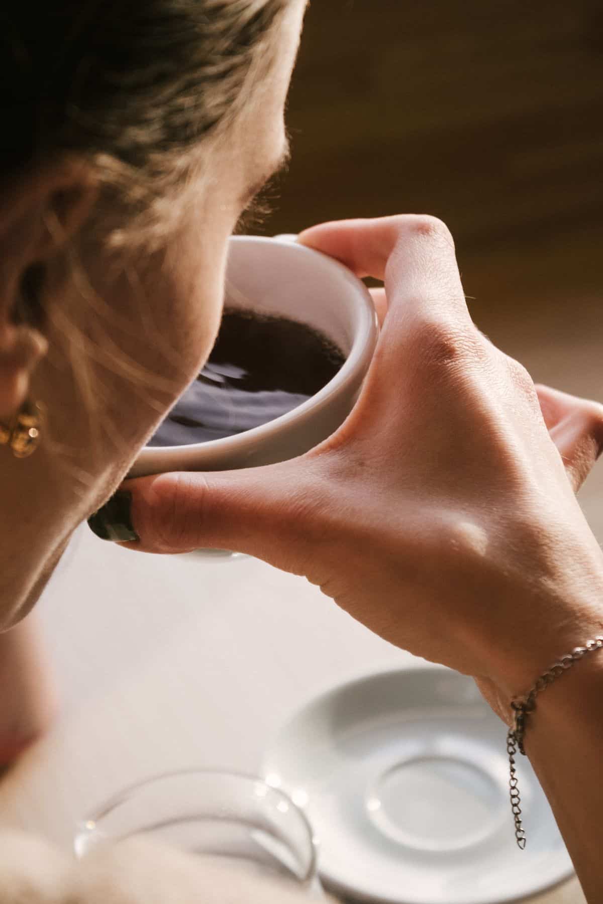 a woman drinking a cup of black coffee.