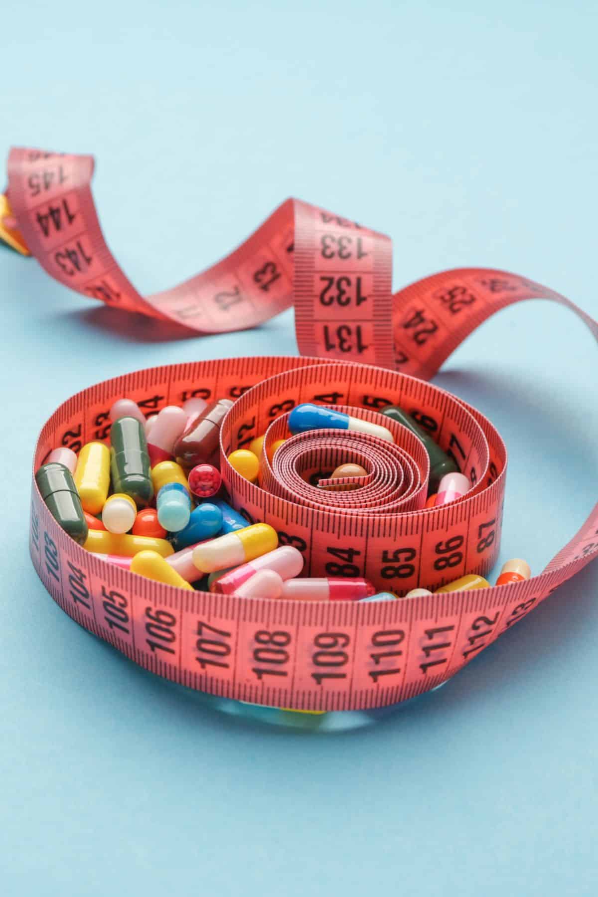 pink measuring tape filled with colorful pills.