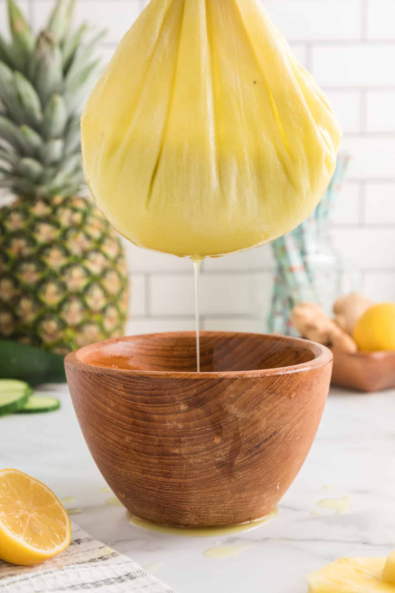 straining pineapple ginger juice in nut milk bag.