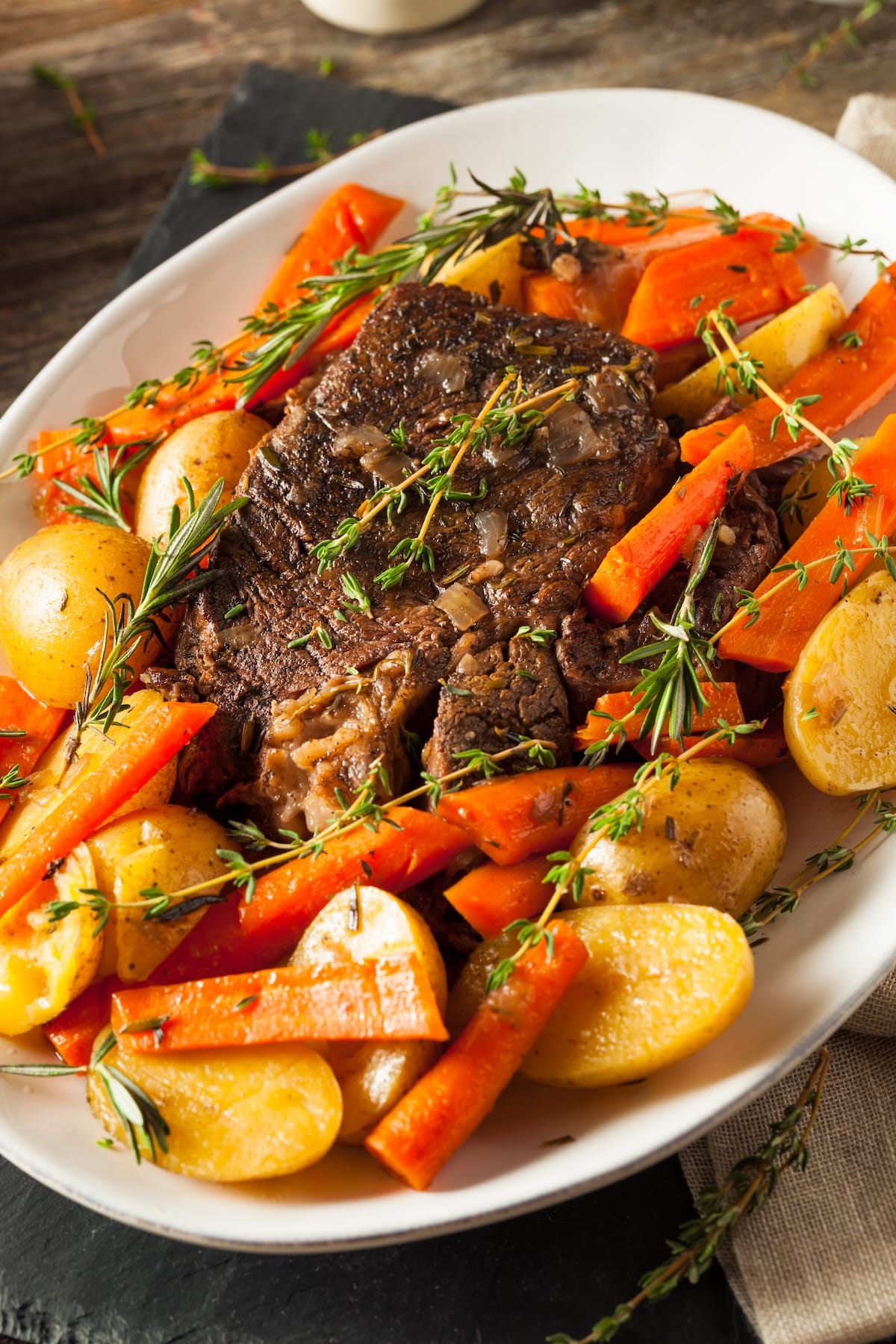 tri tip crockpot roast on serving platter with colorful vegetables.