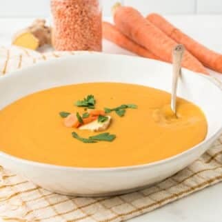 white bowl with orange soup and spoon.