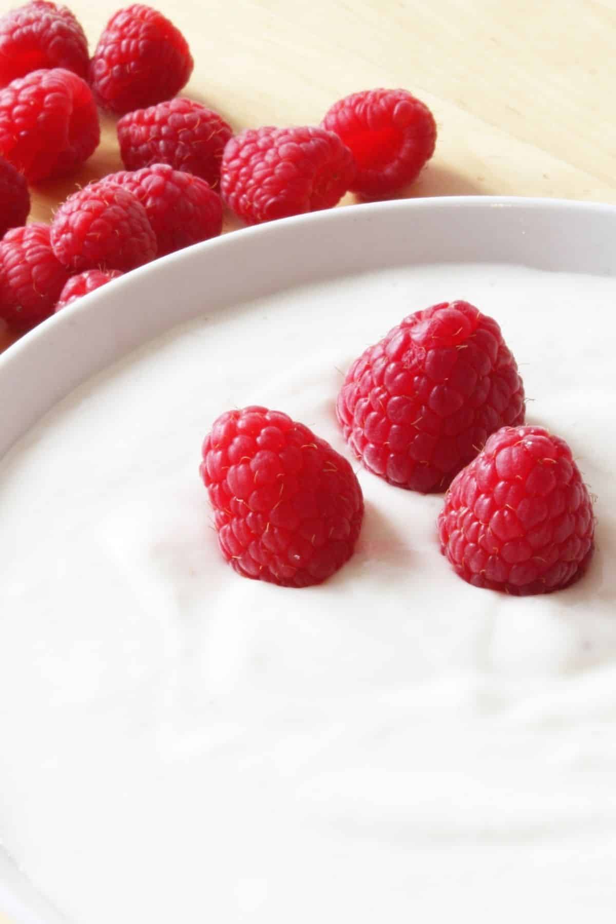 a bowl of yogurt topped with raspberries.